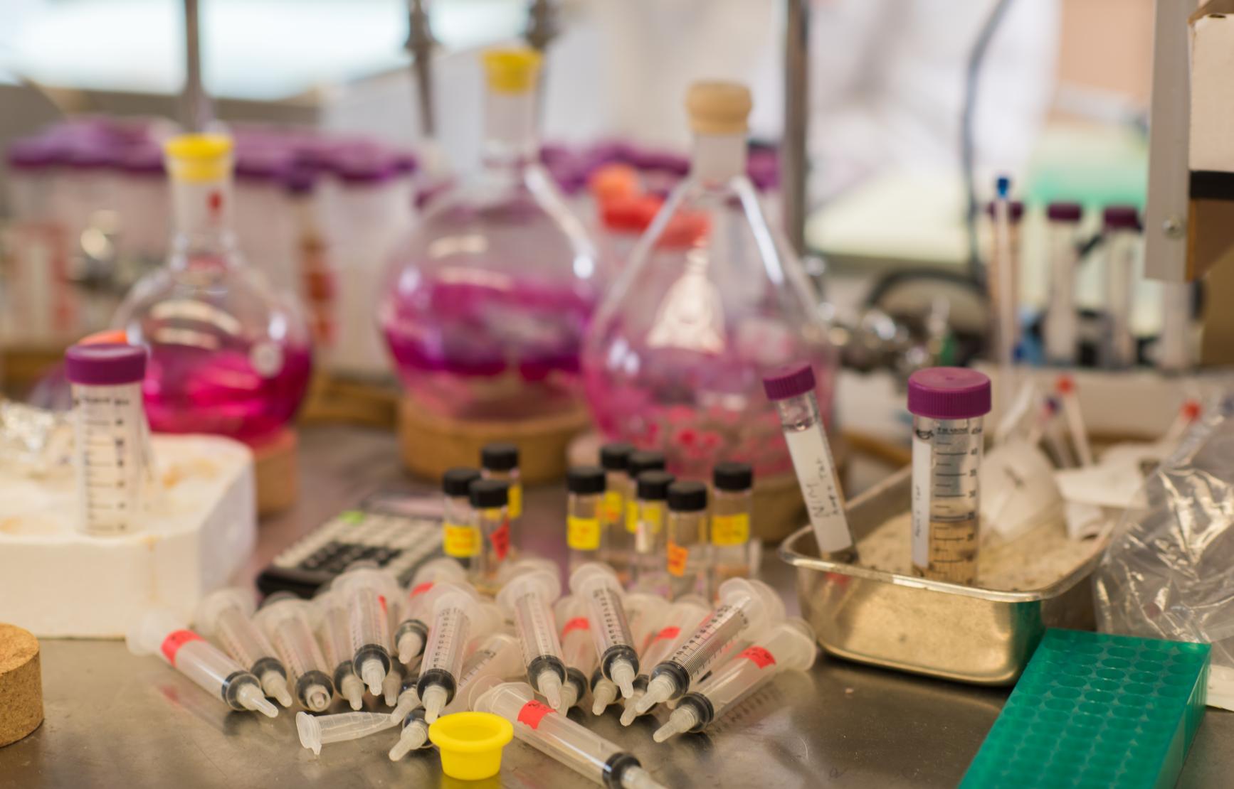 Photo of a lab counter covered in beakers, syringes, and measuring cups.